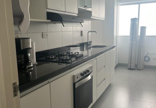 En venta departamento en Miraflores con cocina. Equipada con muebles altos y bajos. Se aprecia el área para una mesita con luz natural desde una ventana grande.